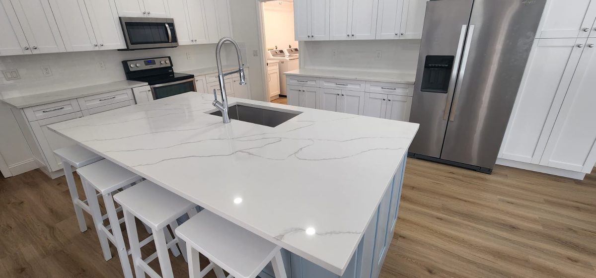 Quartz waterfall island with bar seating and farmhouse sink