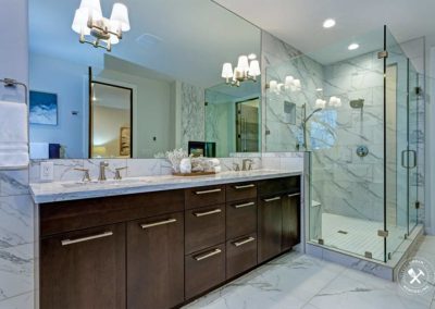 Incredible master bathroom with Carrara marble tile surround, modern glass walk in shower, espresso dual vanity cabinet and a freestanding bathtub.